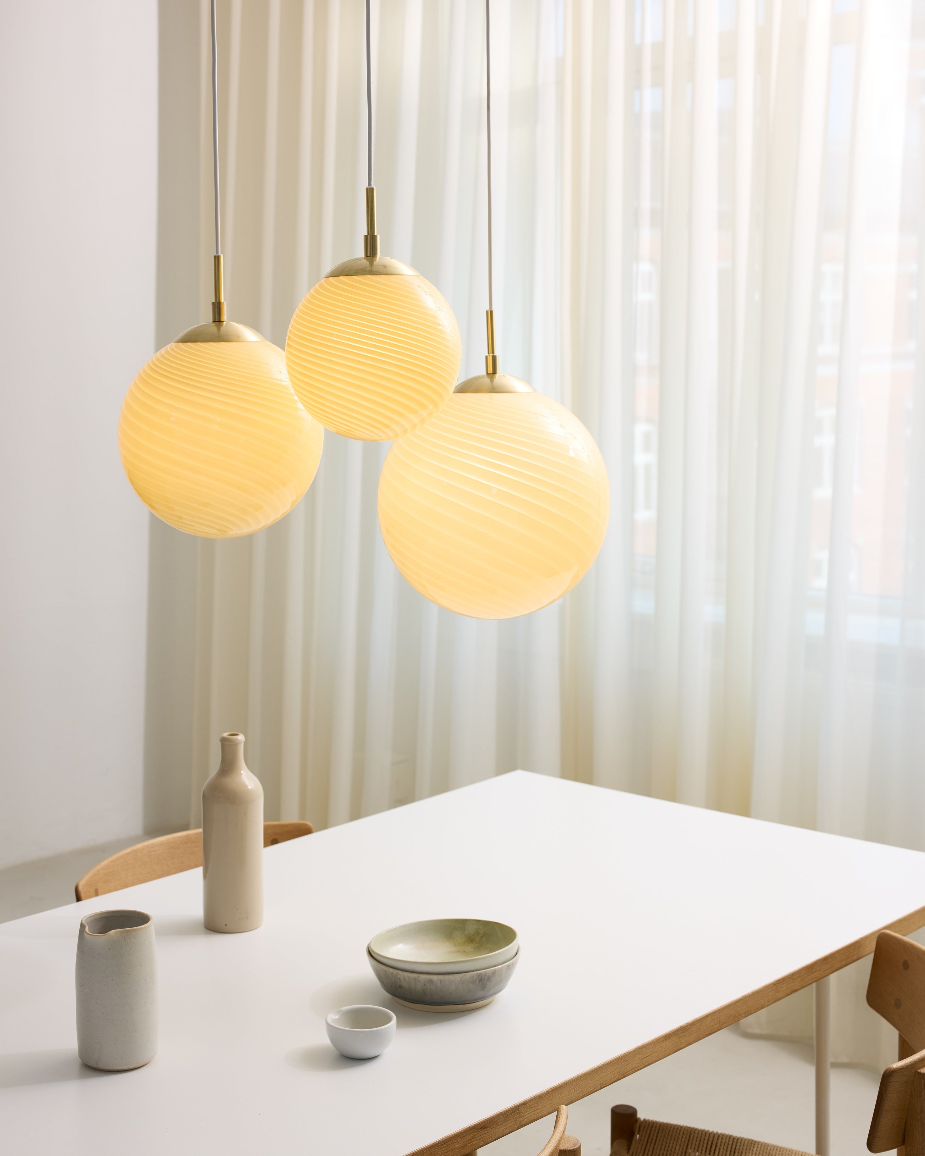 Den æstetiske Candy Ball Pendel Ø30 i Cream hængt op over spisebordet med dens 3 andre størrelser for det elegante look