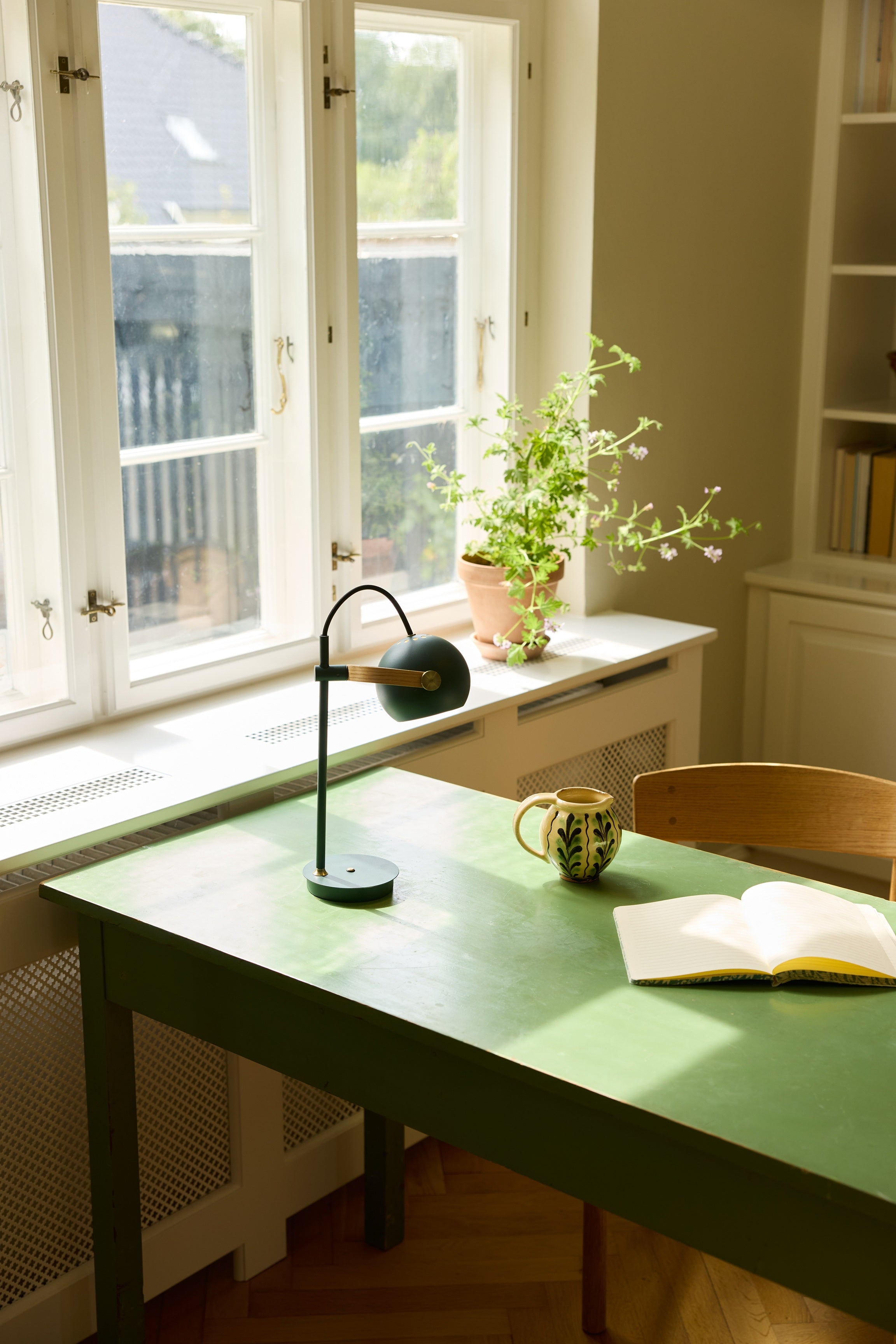 Den æstetiske DC Portable Bordlampe i Grøn placeret i stuen på læsebordet for dens behagelige belysning