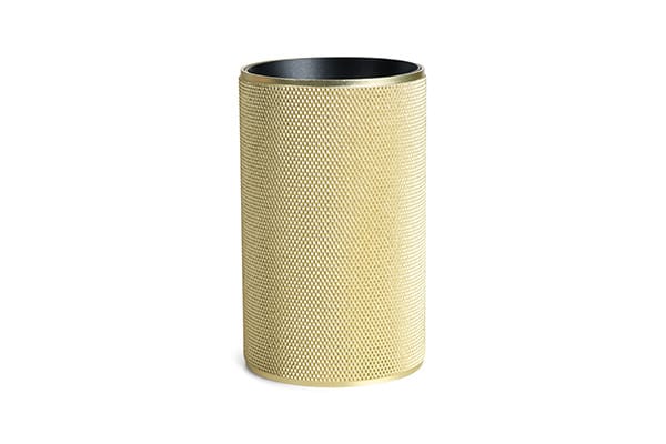 Den unikke og elegante Cylinder i Messing Grib placeret foran en væg