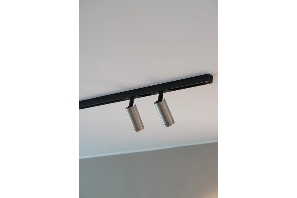 Den æstetiske Designline Domino Mini Spot i Mat Aluminium hængt op i stuen for dens behagelige belysning