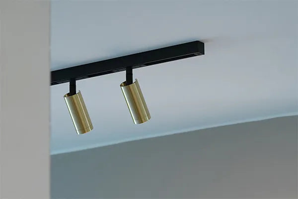 Den æstetiske Designline Domino Mini Spot i Messing hængt op i stuen for dens varme belysning