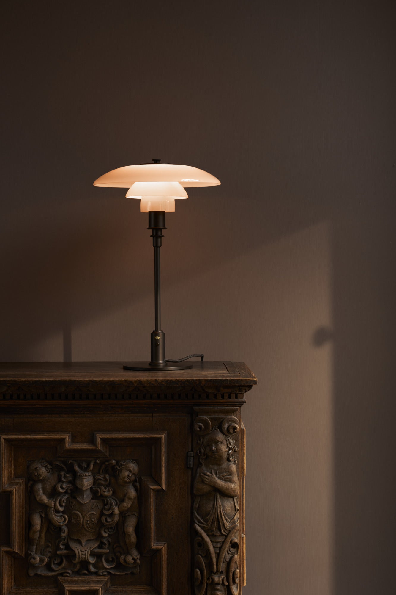 VL Ring Crown Ø150 E14 bordlampe messing/opal på reol i mørket