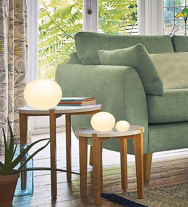 Den æstetiske Globus Ø18 Bordlampe i Hvid placeret på sofabordet for dens varme belysning