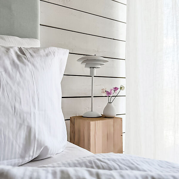 Den elegante Epsilon Bordlampe i Hvid placeret på sengebordet for dens behagelige belysning