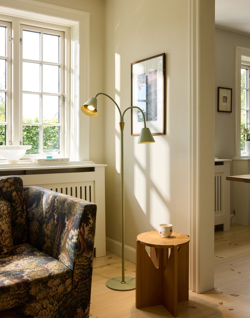 Hygge 2 arme Gulvlampe – Grøn placeret i hjørnet af stuen for dens elegante design fra Halo Design og varme belysning