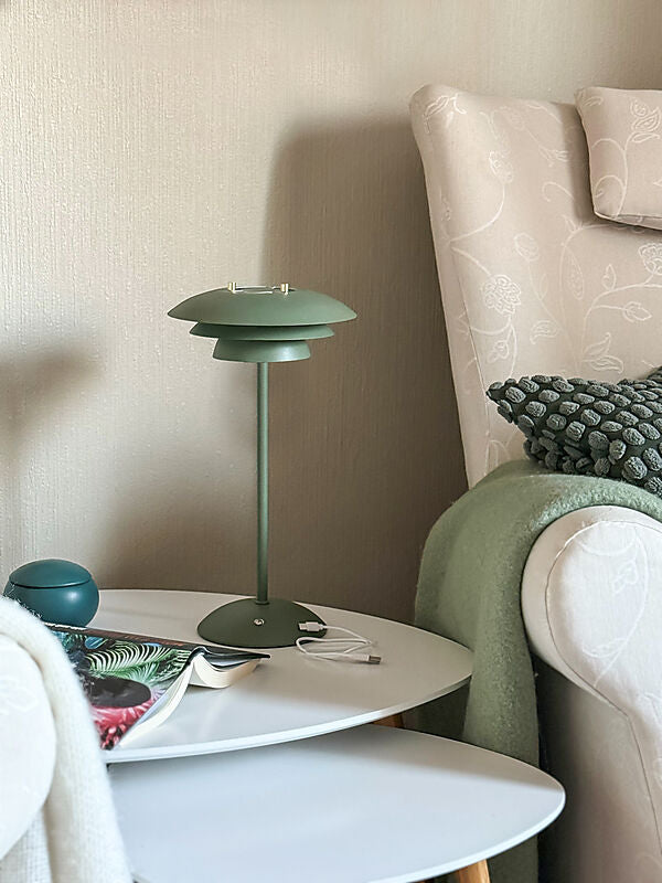 Den æstetiske Epsilon Recharge Bordlampe i Grøn placeret på sofabordet
