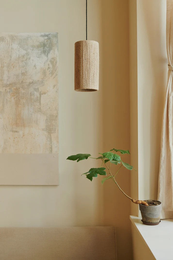 Den æstetiske Ro Ø23 High Pendel i Jute hængt op i hjørnet af stuen for dens behagelige belysning