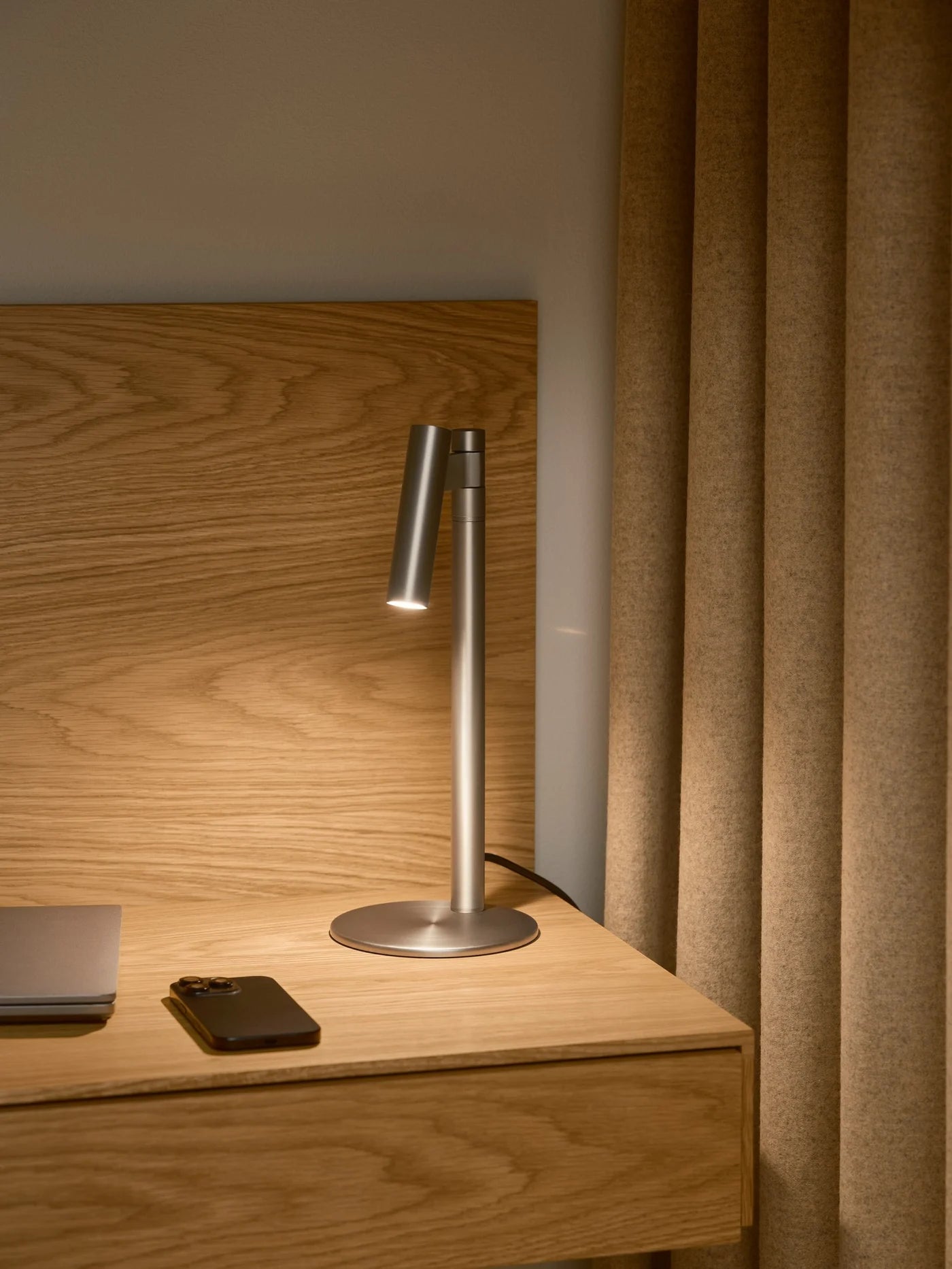 Den unikke designet Makoto Bordlampe i Satin Krom placeret på sengebordet for dens varme belysning