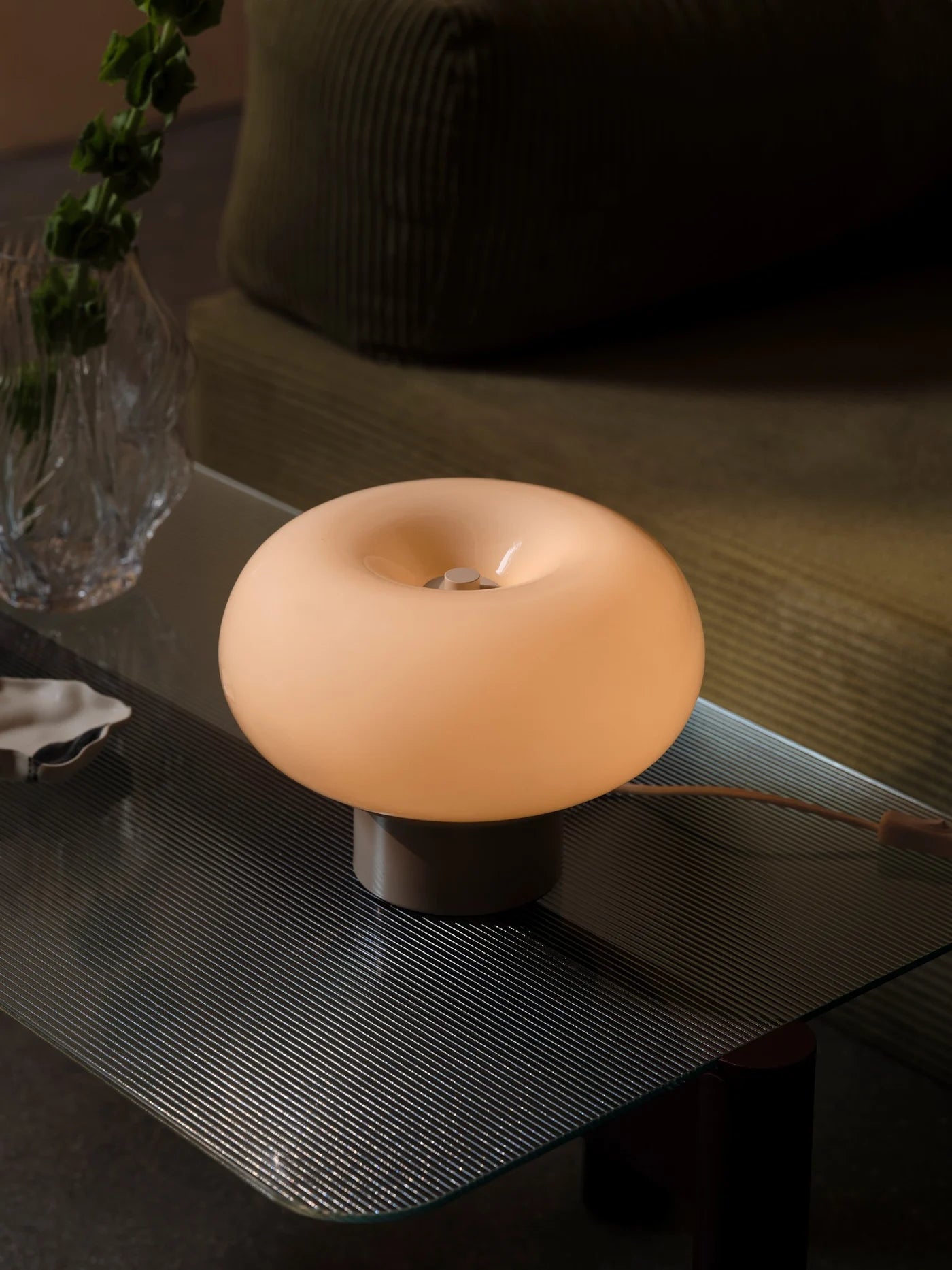 Den æstetiske Malti Bordlampe i Beige placeret på stuebordet for dens hyggelige belysning
