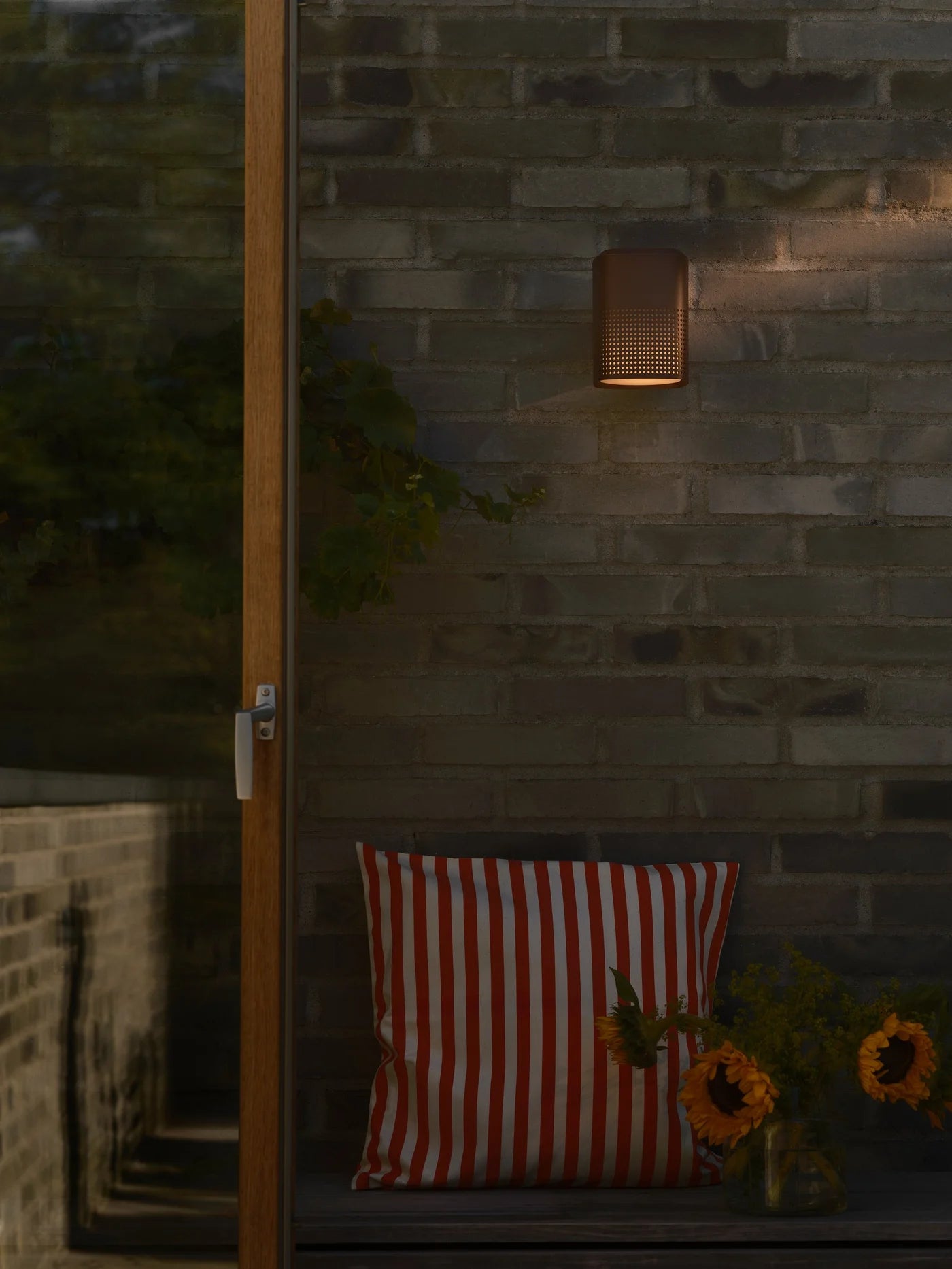 Den elegante skandinaviske designet Sidara Væglampe Seaside i Metallisk Brun hængt op i hjørnet af terrassen for dens behagelige belysning