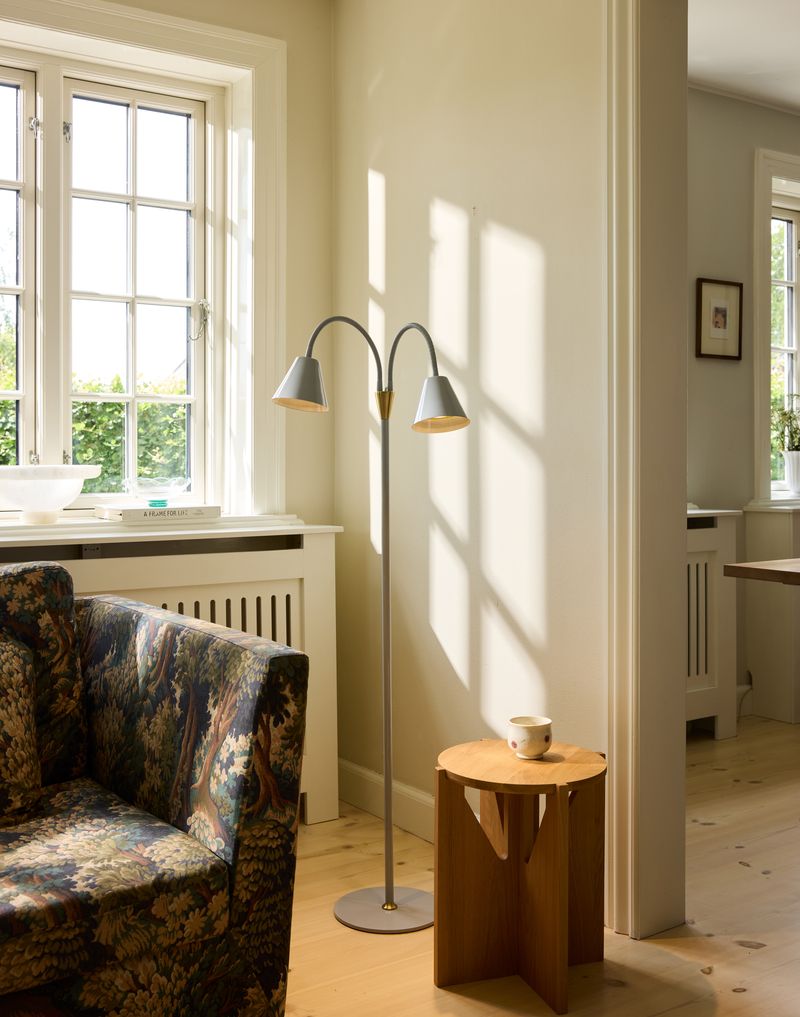 Hygge 2-arm Gulvlampe Grå placeret i hjørnet af stuen for dens varme belysning og elegante design