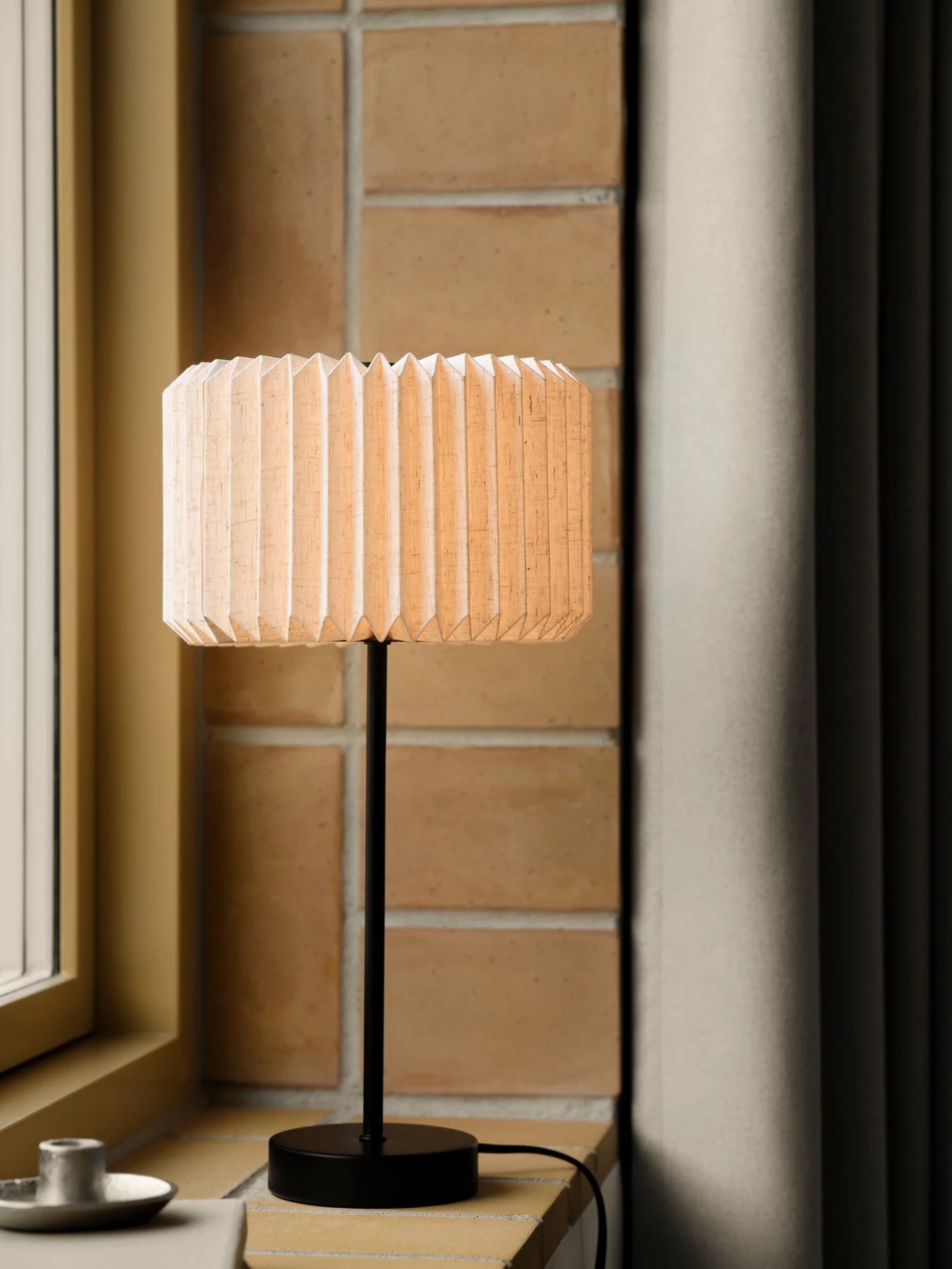Den æstetiske Vivienne Bordlampe i Sort placeret i vindueskammen i stuen for dens behagelige belysning