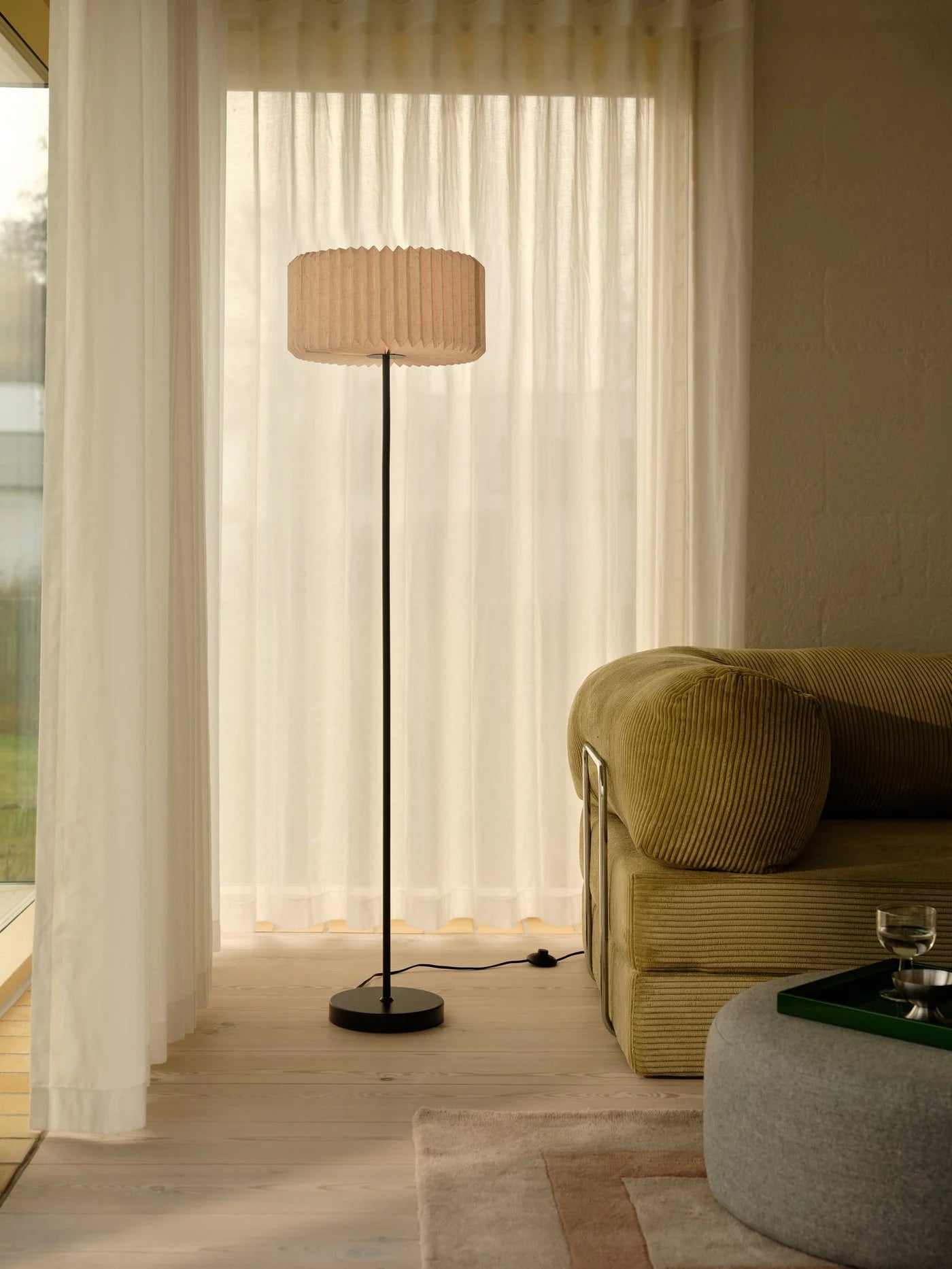 Den elegante designet Vivienne Gulvlampe i Sort placeret i hjørnet af stuen for dens behagelige belysning