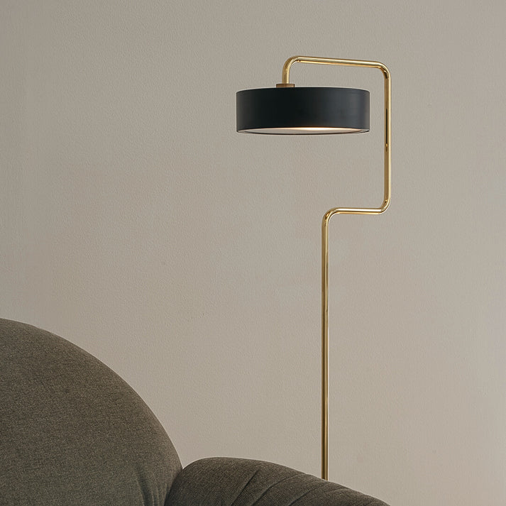 Den unikke og skandinaviske designet Petite Machine Gulvlampe i Sort placeret ved siden af sofaen for dens behagelige og varme belysning i hele rummet