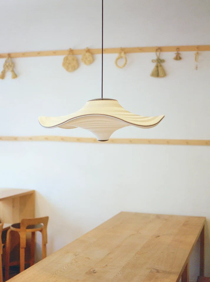 Den elegante og simple designet Flying Ø58 i Golden Sand hængt op over spisebordet for dens behagelige belysning