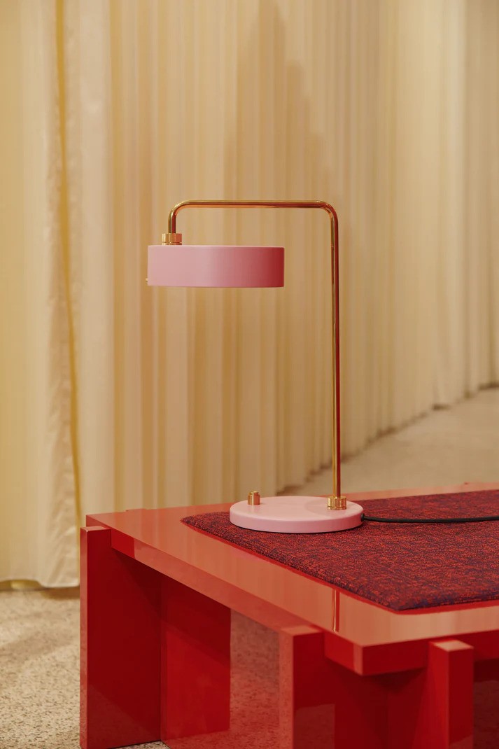 Den æstetiske og skandinaviske designet Petite Machine Bordlampe i Lys Pink placeret på bordet i stuen for dens varme belysning