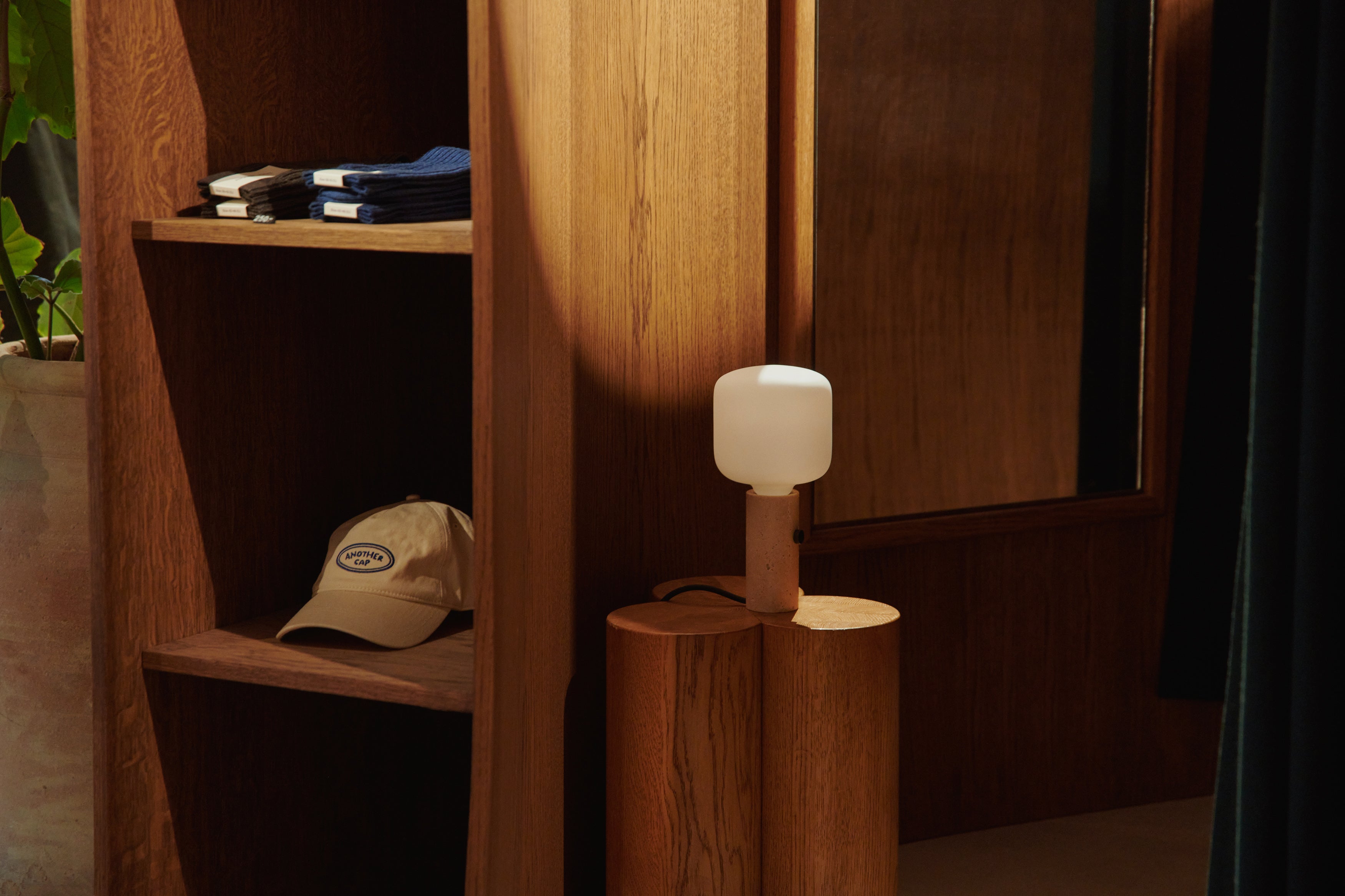 Den unikke og simple designet Core lampe i Creme Travertin placeret i en tøjbutik for dens behagelige belysning