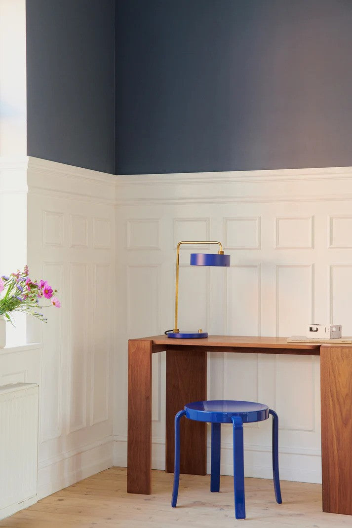 Den unikke og elegante designet Petite Machine Bordlampe i Royal Blå placeret på læsebordet for dens behagelige belysning