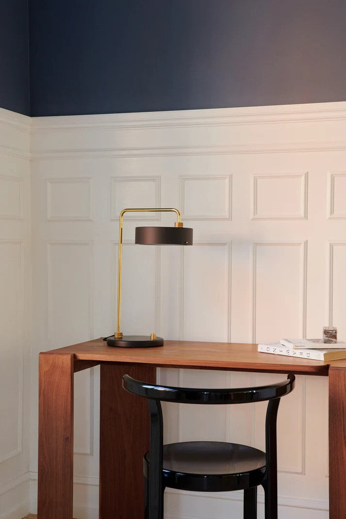 Den æstetiske Petite Machine Bordlampe i Sort placeret på læsebordet for dens behagelige belysning