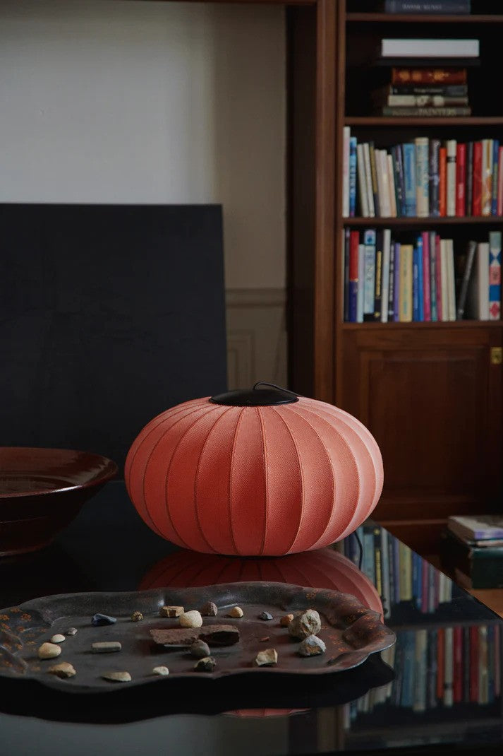 Den æstetiske Knit-Wit Ø57 Oval Pendel LED i Coral placeret på sofabordet