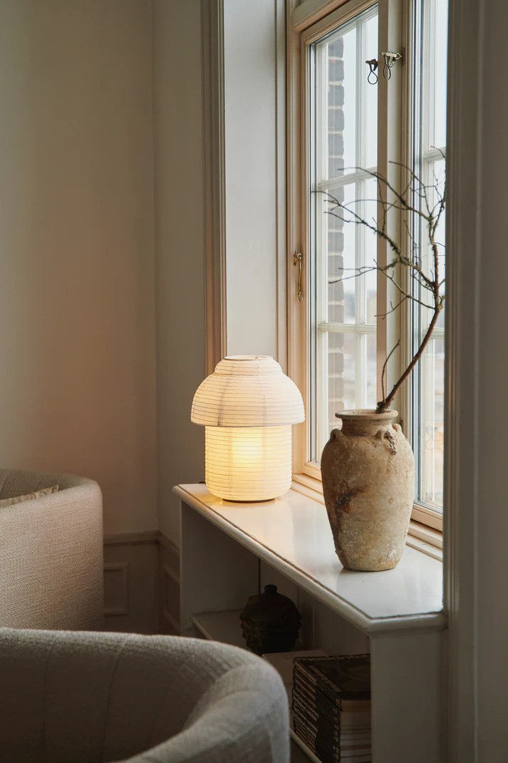 Den æstetiske Papier Ø30 Bordlampe i Hvid placeret i vindueskammen med en E27 pære iført og tændt for dens behagelige belysning
