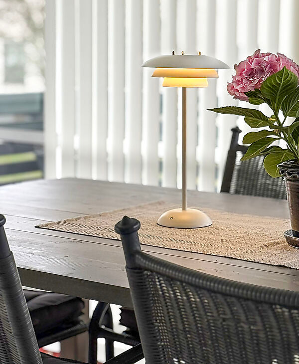 Den æstetiske Epsilon Recharge Bordlampe i Hvid placeret på spisebordet for dens behagelige belysning