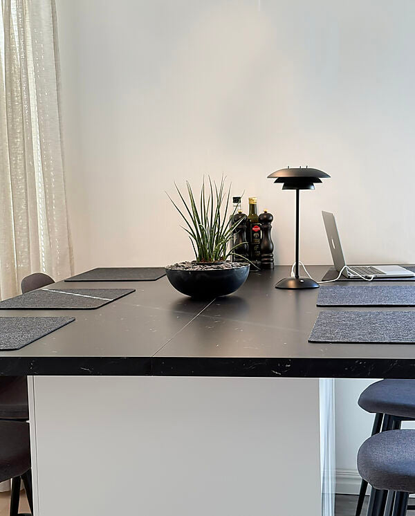 Den elegante designet Epsilon Recharge Bordlampe i Sort placeret på spiseboret for dens behagelige belysning