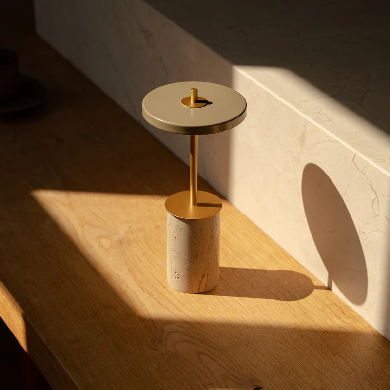Den unikke designet Asteria Move Mini i Clay Travertine Messing placeret i stuen for dens varme belysning