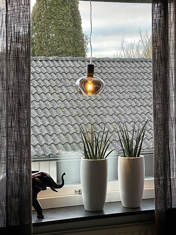 Den unikke designet Bell Pendel i Sort/Røgfarvet hængt op i vindueskammen