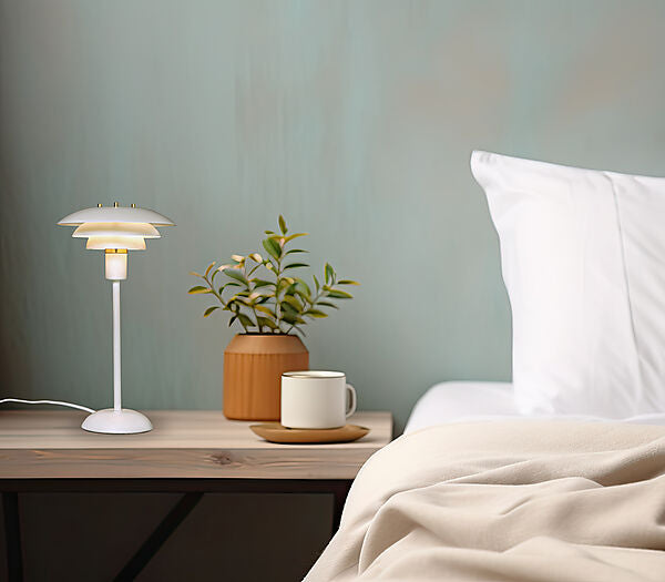 Den æstetiske Epsilon Bordlampe i Hvid placeret i hjørnet af soveværelset for dens varme belysning
