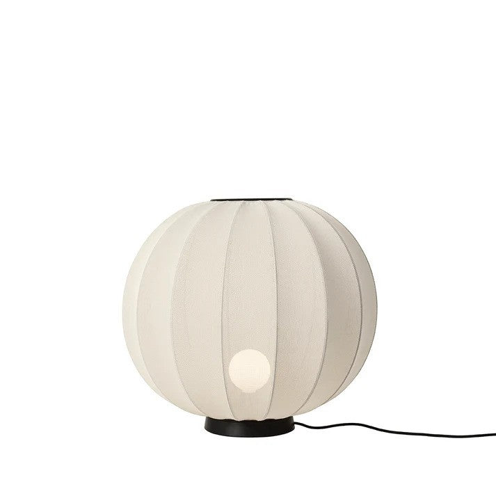 Den æstetiske Knit-Wit Ø60 Round Gulvlampe Level i Pearl White placeret foran en hvid væg og iført en tændt E27 pære