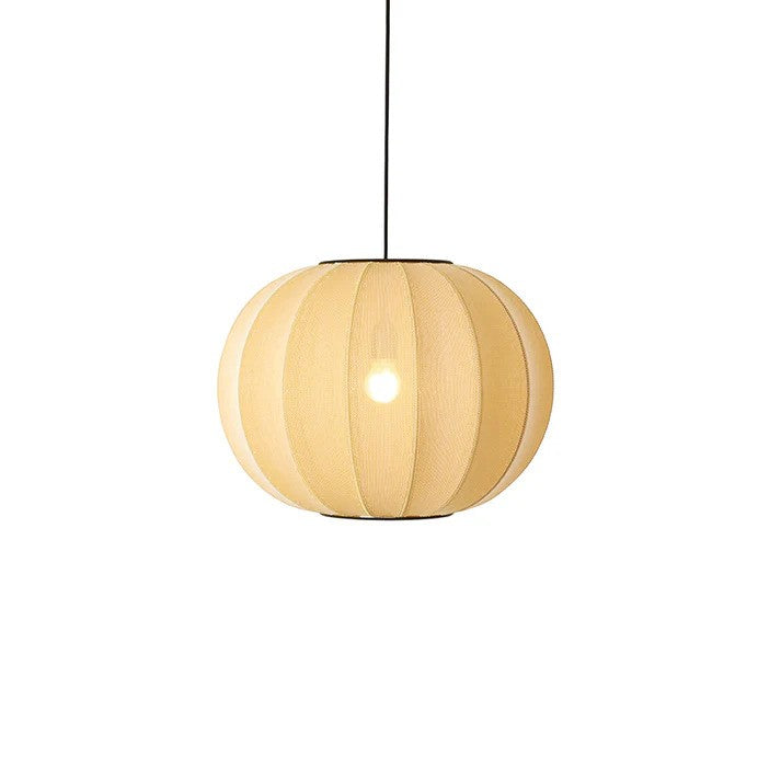 Den unikke og elegante designet Knit-Wit Ø45 Round Pendel i Sunrise hængt op foran en hvid væg med en tændt E27 pære
