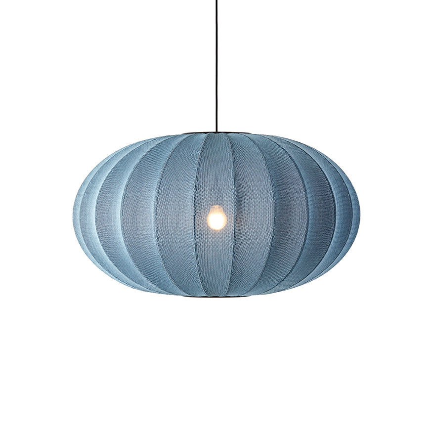 Den æstetiske Knit-Wit Ø76 Oval Pendel i Blue Stone hængt op foran en hvid væg for en flot kontrast