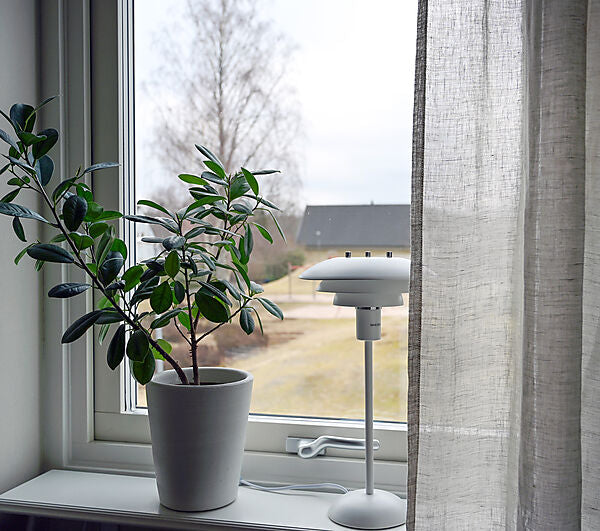 Den elegante Epsilon Bordlampe i Hvid placeret i vindueskammen