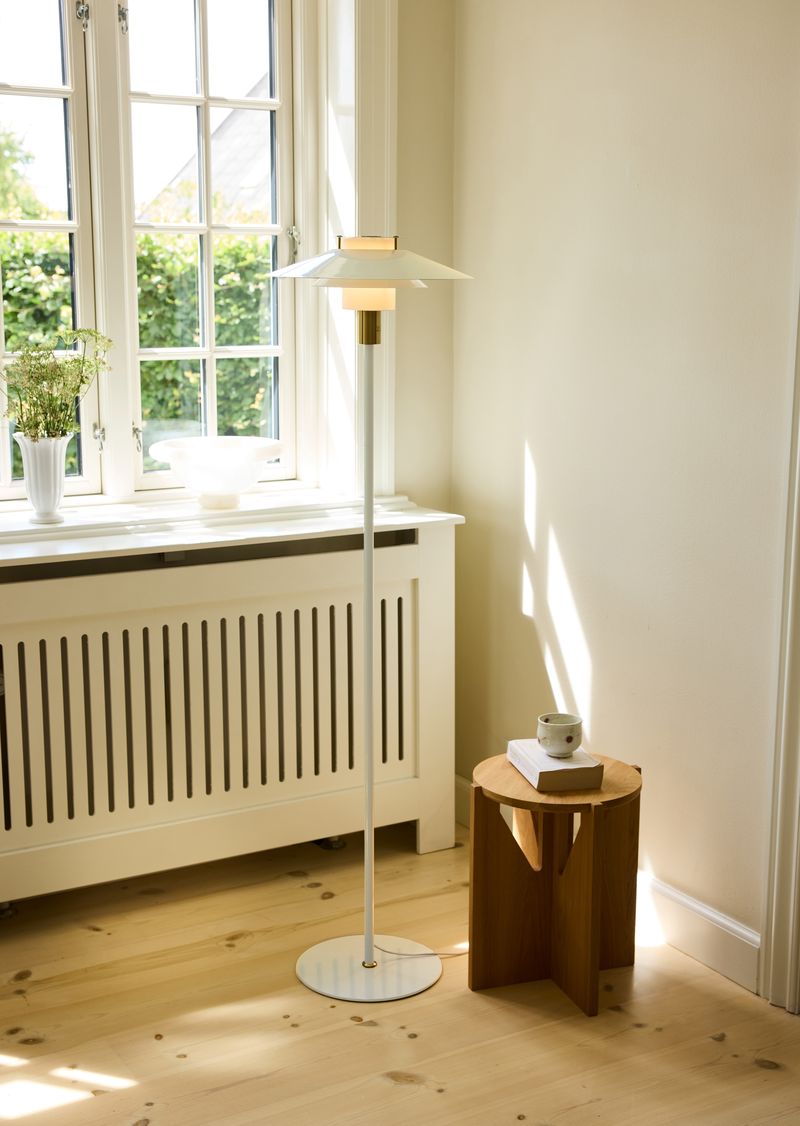 Rivoli Gulvlampe Ø40 Cream/Messing placeret i hjørnet af stuen for dens elegante design