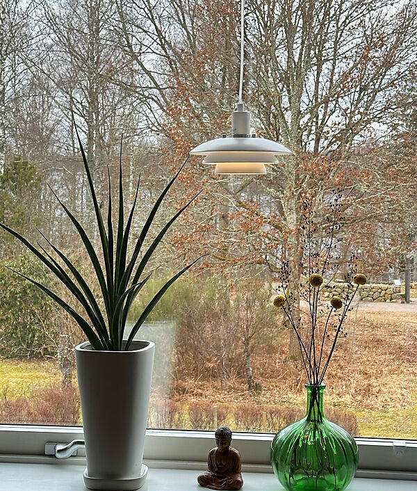 Den æstetiske Epsilon Ø20 Pendel i Hvid placeret i vindueskammen for dens behagelige belysning