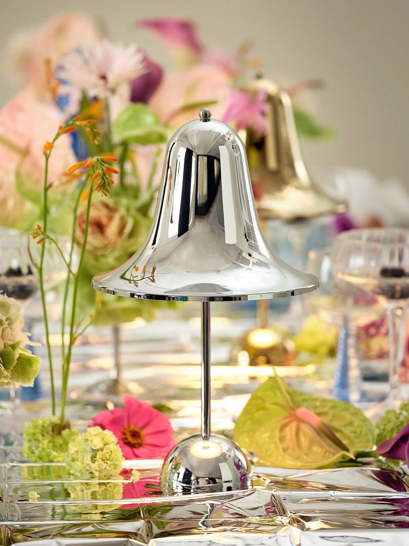 Kromfarvet Pantop Portable lampe på et bord med blomster